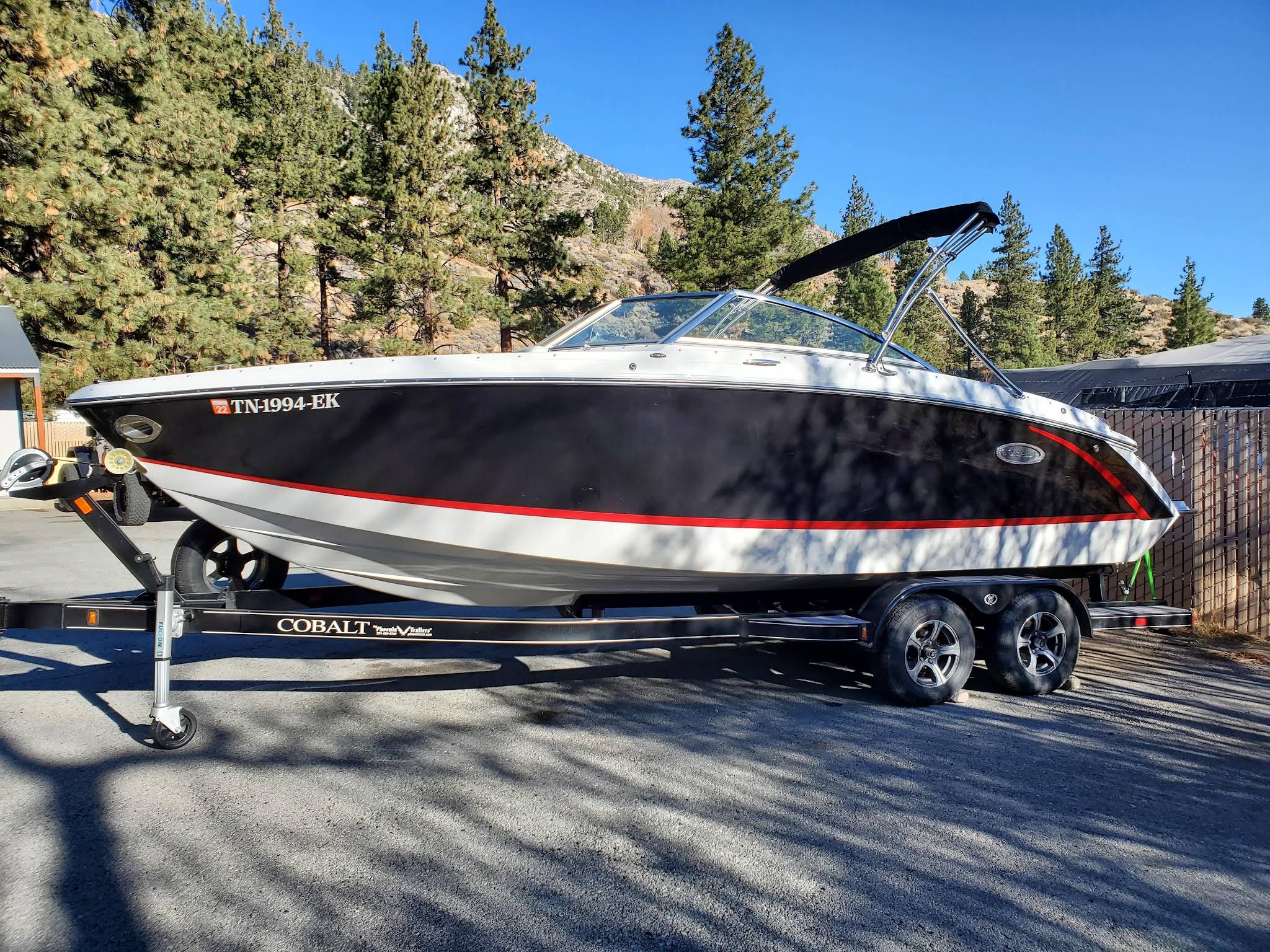 Boat on a trailer at Tahoe Camper Storage, with pine trees and the Sierra landscape behind it